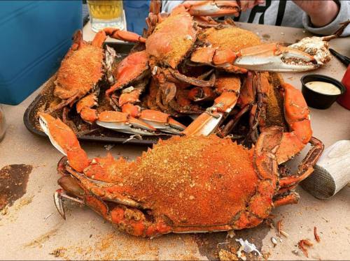 A tray of seasoned crabs, some whole and others partially cracked, with a side of dipping sauce.