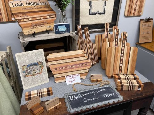 A display of handcrafted wooden cutting boards and kitchen items, featuring various designs and prices.