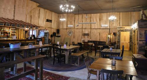 Cozy interior of a rustic bar with wooden tables, chairs, chandeliers, and a warm, inviting atmosphere.