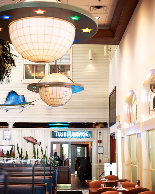 Interior of a sushi restaurant featuring UFO-shaped light fixtures and a vibrant, welcoming atmosphere.