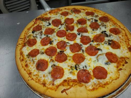 A large pizza topped with pepperoni, cheese, and mushrooms on a metal surface.