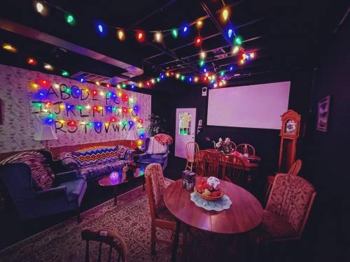 Cozy room with colorful string lights, a vintage clock, and a wall featuring the alphabet, reminiscent of a retro setting.