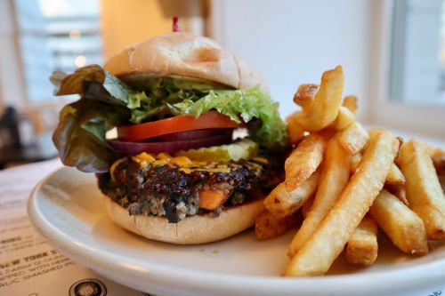 A delicious burger with lettuce, tomato, onion, and pickles, served with a side of crispy French fries.