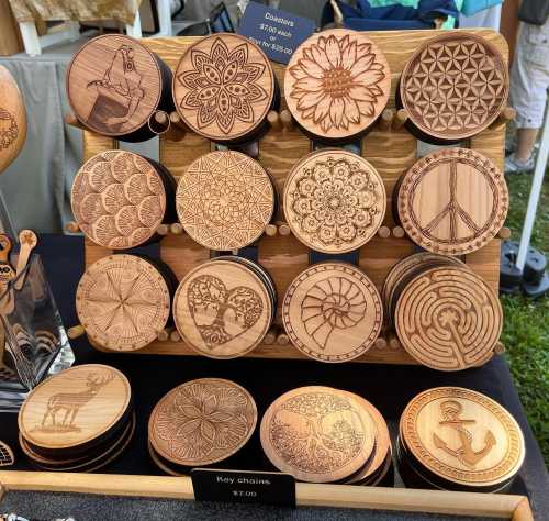 A display of wooden keychains featuring intricate laser-etched designs, including flowers, patterns, and symbols.