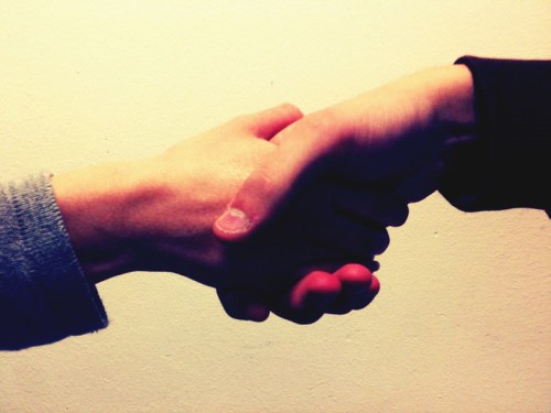 Two hands shaking against a plain background, symbolizing agreement or partnership.