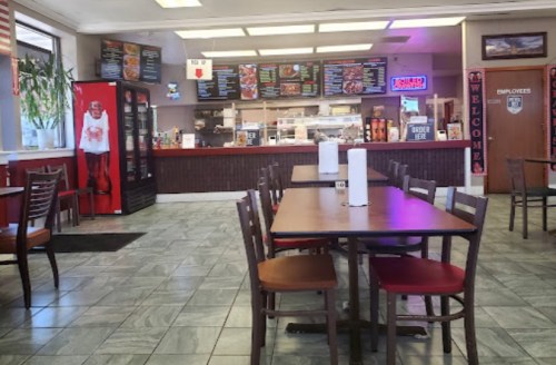 Interior of a casual dining restaurant with empty tables, a counter displaying menu items, and a welcoming atmosphere.
