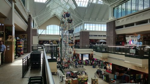 A spacious indoor shopping mall featuring a large Ferris wheel and various shops on multiple levels.