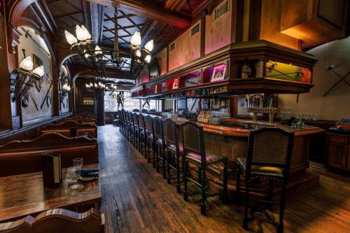 A stylish bar with wooden decor, high stools, and colorful lighting, set in a cozy restaurant interior.