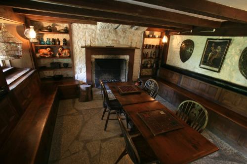 Cozy room with wooden beams, a fireplace, and a table surrounded by benches and shelves of decorative items.