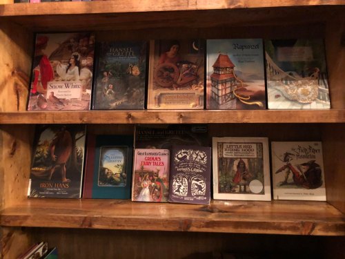 A wooden bookshelf filled with various fairy tale books, including "Snow White," "Hansel and Gretel," and "Little Red Riding Hood."