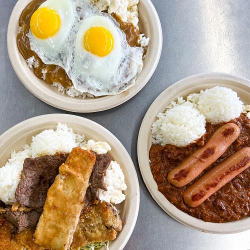Three plates of food: two with rice, fried eggs, and meats; one with rice, sausages, and a red sauce.