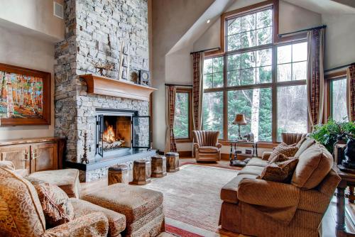 Cozy living room with a stone fireplace, large windows, and comfortable seating, surrounded by nature.