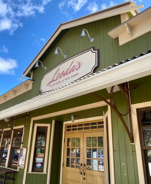 Exterior of Leoda's Kitchen and Pie Shop, featuring a green facade and a sign, under a blue sky with clouds.