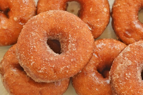 A close-up of freshly baked, sugar-coated donuts arranged in a pile.