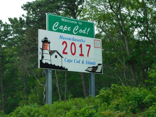 Welcome sign for Cape Cod featuring a lighthouse and the year 2017, surrounded by greenery.