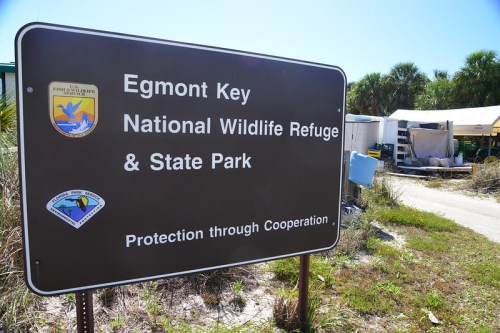 Sign for Egmont Key National Wildlife Refuge & State Park, featuring logos and the phrase "Protection through Cooperation."