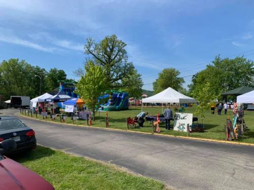 A community event with tents, a bounce house, and people enjoying the outdoors on a sunny day.