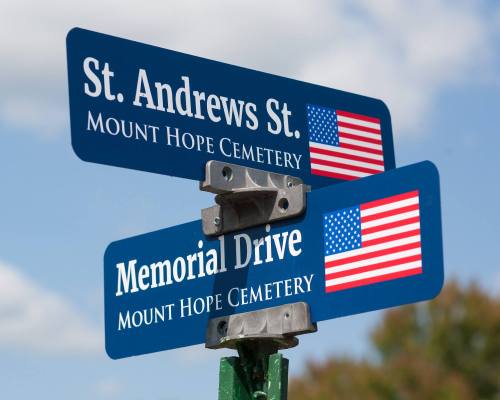 Street signs for St. Andrews St. and Memorial Drive, both indicating Mount Hope Cemetery, with American flags.