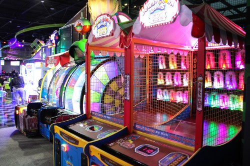 Colorful arcade games with bright lights and a carnival theme, featuring a spinning wheel and a basketball shooting game.