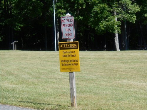 A sign indicating no pets allowed and a warning about smoking being prohibited at a clean air beach.