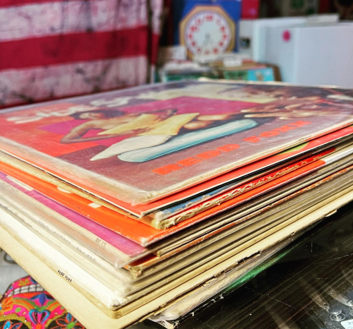 A stack of colorful vinyl record covers displayed on a table, showcasing various album designs.