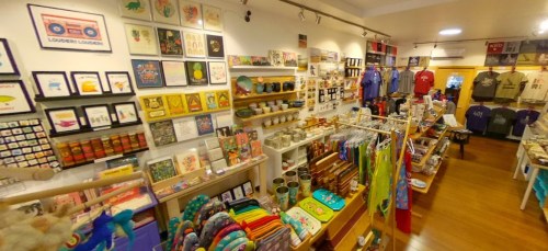 A colorful shop interior filled with art prints, crafts, clothing, and various handmade items on display.