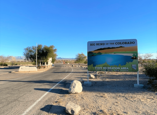 Sign for Big Bend of the Colorado State Recreation Area at the entrance, with a clear blue sky and desert landscape.