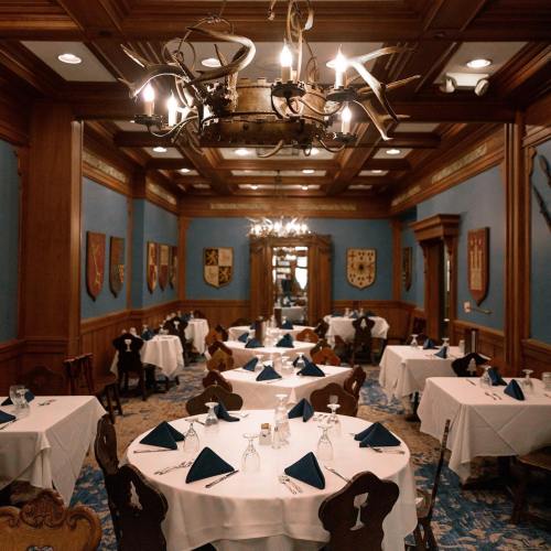 Elegant dining room with wooden decor, blue walls, and tables set with white tablecloths and blue napkins.