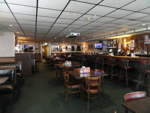 Interior of a casual restaurant with tables, chairs, a bar area, and a TV on the wall. Warm lighting and a cozy atmosphere.