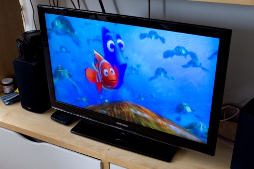 A television displaying a scene from an animated underwater movie featuring a blue fish and an orange clownfish.