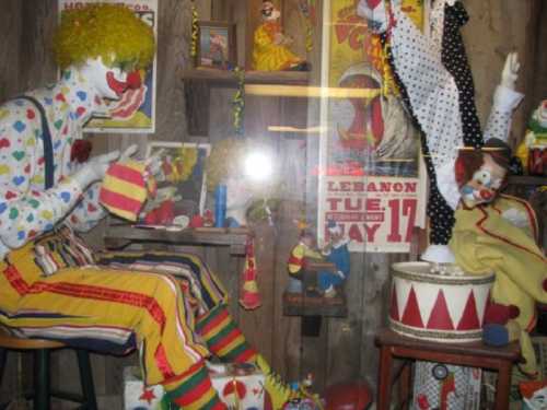 A colorful display of clowns in a vintage setting, with one clown sewing and another playing a drum.