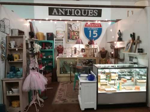A cozy antique shop display featuring vintage items, a glass case, and decorative signs.