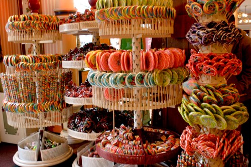 Colorful candy displays featuring various lollipops and sweets arranged on tiered stands in a shop.