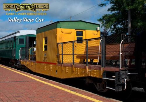 A yellow caboose labeled "Valley View Car" next to a green train car on a brick platform at a railroad museum.
