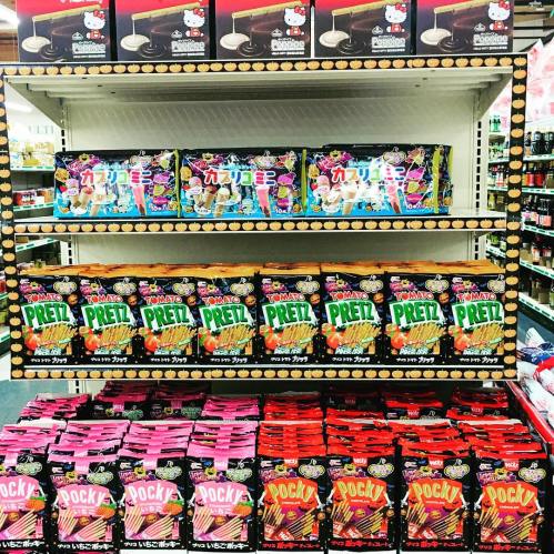 A colorful display of various snacks, including Hello Kitty treats, Pretz, and Pocky, on a store shelf.