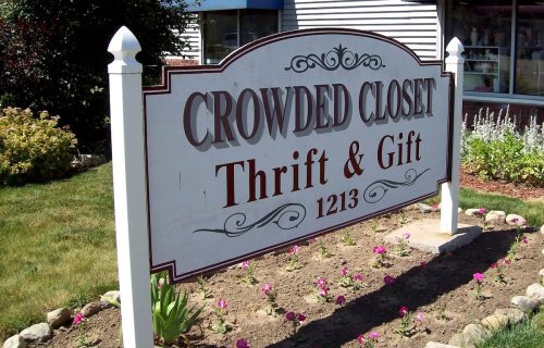 Sign for "Crowded Closet Thrift & Gift" with flowers and greenery in the foreground. Address: 1213.