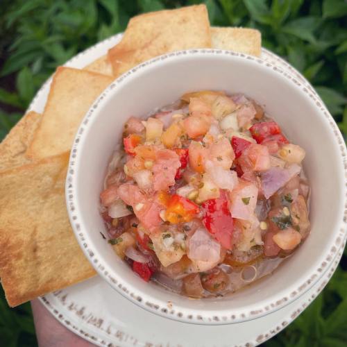 A bowl of fresh salsa with diced tomatoes, onions, and peppers, served with crispy tortilla chips on the side.