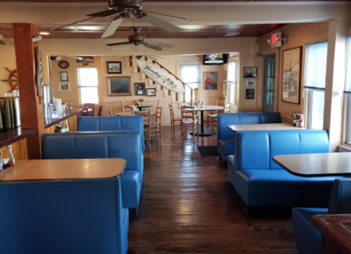 Interior of a cozy diner featuring blue booths, wooden floors, and nautical decor. Bright and inviting atmosphere.