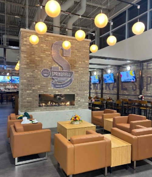 Modern restaurant interior featuring a brick wall, round pendant lights, and cozy seating arrangements.
