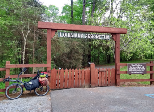 Entrance to the Louisiana Arboretum with a bicycle parked nearby, surrounded by lush greenery.