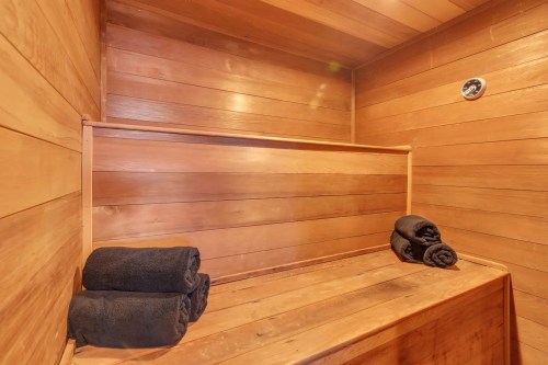 A wooden sauna interior featuring a bench and neatly rolled black towels.