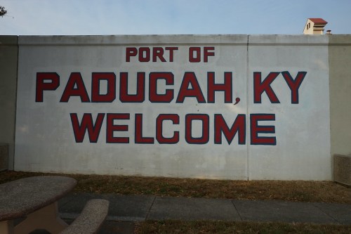 Mural reading "Port of Paducah, KY Welcome" on a concrete wall, with a picnic table in the foreground.