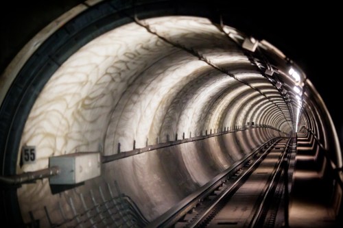 A dimly lit subway tunnel with curved walls and tracks leading into the distance.