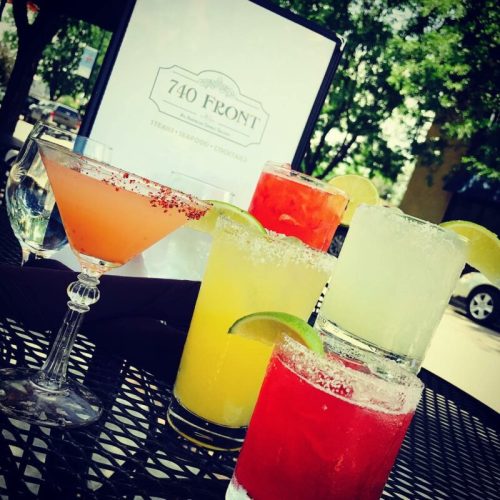 A variety of colorful cocktails on a table, with a menu for 740 Front in the background.
