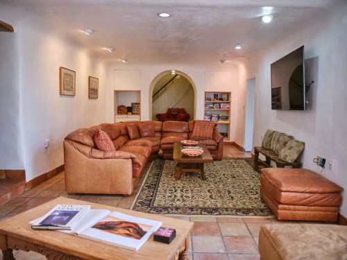 Cozy living room with a large sectional sofa, coffee table, and TV, featuring warm tones and a patterned rug.