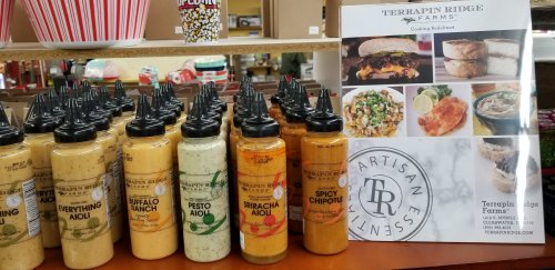 A display of various sauces in bottles, alongside a menu featuring dishes from Terrapin Ridge Farms.