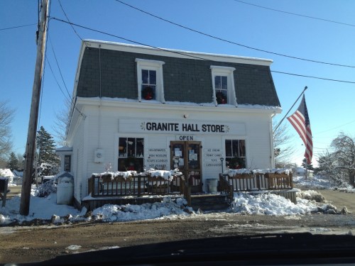 A quaint store with a green roof, snow-covered surroundings, and an American flag, labeled "Granite Hall Store."