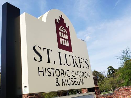 Sign for St. Luke's Historic Church & Museum against a clear blue sky.