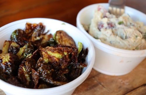 Two bowls of food: one with crispy Brussels sprouts and another with creamy potato salad.