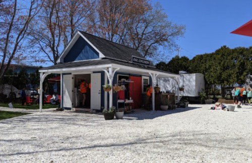 A small blue and red building with a porch, surrounded by gravel and trees, serving as a park information center.